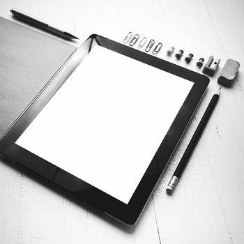 tablet with office supplies over white table black and white color style