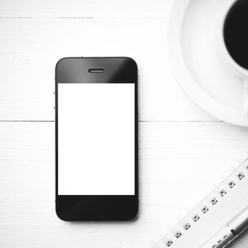 cellphone with notebook and coffee cup over white table black and white color style