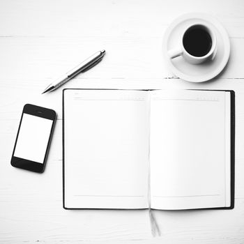 cellphone with notebook and coffee cup over white table black and white color style