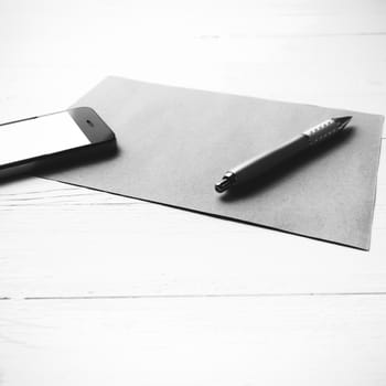 cellphone with brown paper and pen over white table black and white color style