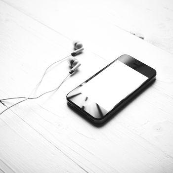 cellphone with earphone over white table black and white color style