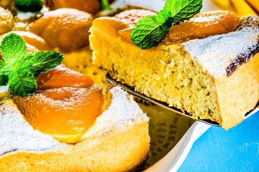 Homemade fresh apricot cake on blue wood table with yellow napkin