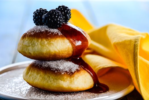 two delicious german doughnuts with blackberry and blackberry sauce on white plate