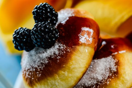 two delicious german doughnuts with blackberry and blackberry sauce and yellow napkin