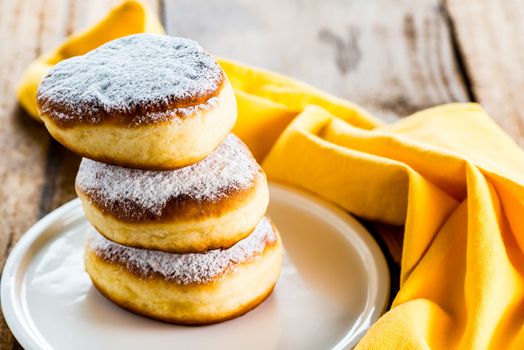 three delicious german doughnuts powdered with sugar on white plate