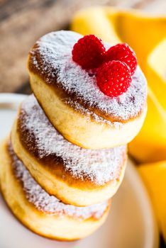 A stack of tree delicious german doughnuts powdered with sugar and raspberry on the top