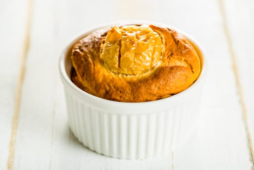Small cake with apple in a ramekin on white wood table