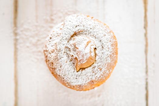 Top view of a small apple cake powdered with sugar on white wood table