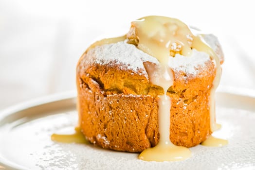 Small cakes with apple powdered with sugar and coated with vanilla sauce on white wood table