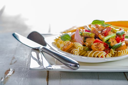 White pasta plate with vegetables and sausage on white background