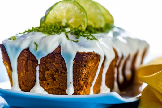 lemon loaf cake with icing decorating with lemon on white plate and blue wood table