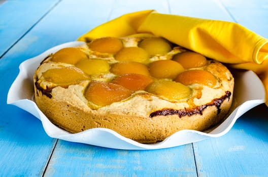 Homemade fresh apricot cake on blue wood table with yellow napkin