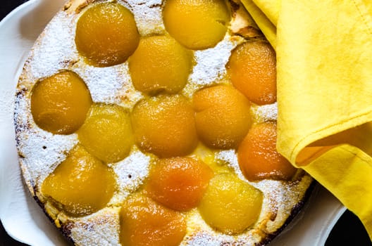 Homemade fresh apricot cake on blue wood table with yellow napkin