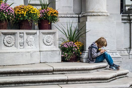 NEW YORK, USA, October 09, 2015: An unidentified boy reading a book at Bryant Park in Manhattan, New York City.