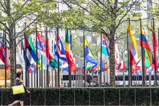 NEW YORK, USA, October 10, 2015: An unidentified woman walks in front of Rockfeller Center flags in Manhattan, New York.