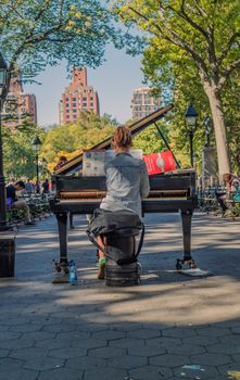 NEW YORK, USA, October 10, 2015: An unidentified lonely girl plays her piano in Washington Square Garden in Manhattan, New York.