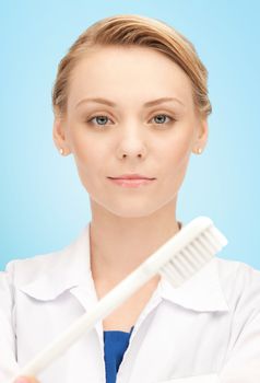 people, medicine, stomatology and healthcare concept - happy young female dentist with tooth brush over blue background