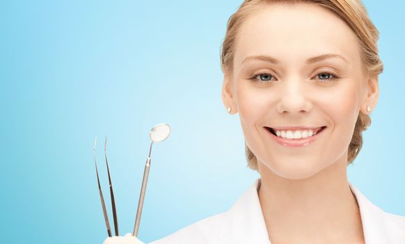 people, medicine, stomatology and healthcare concept - happy young female dentist with tools over blue background