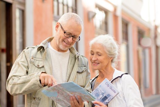 family, age, tourism, travel and people concept - senior couple with map and city guide on street