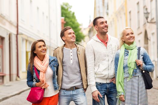 friendship, travel and vacation concept - group of smiling friends walking in the city