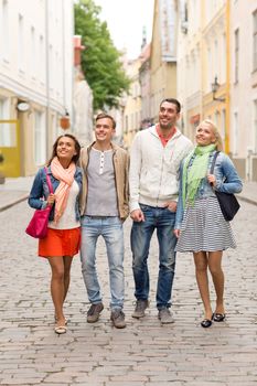 friendship, travel and vacation concept - group of smiling friends walking in the city