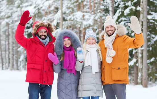 love, relationship, season, friendship and people concept - group of smiling men and women waving hands in winter forest