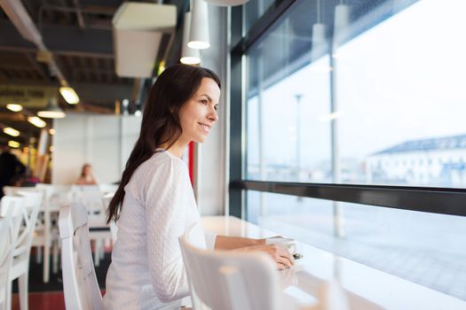 leisure, drinks, people and lifestyle concept - smiling young woman drinking coffee at cafe