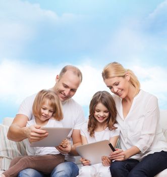 family, technology and people - smiling mother, father and little girls with tablet pc computers over blue sky background