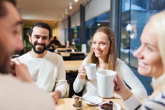 people, leisure, communication, eating and drinking concept - happy friends meeting and drinking tea or coffee at cafe