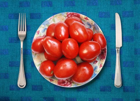 red tomatoes on white plate, knife and fork