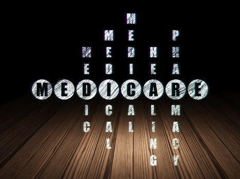 Healthcare concept: Glowing word Medicare in solving Crossword Puzzle in grunge dark room with Wooden Floor, black background