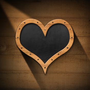 Empty blackboard with wooden frame in the shape of a heart. Hanging on a wooden wall with planks