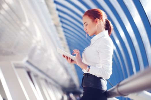 Beautiful modern businesswoman using tablet computer inside modern building