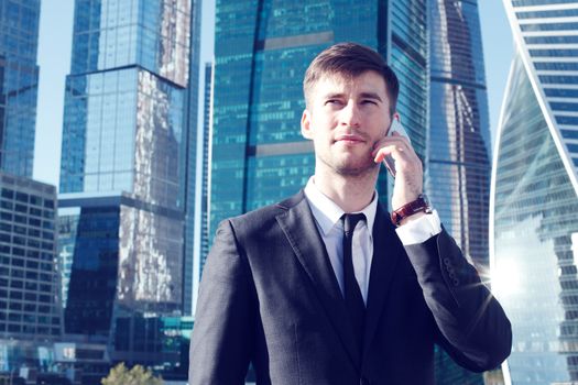 Businessman talking on the phone on skyscraper background