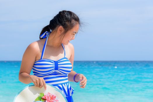 Tourist girl in a blue white striped swimsuit standing with happiness on the beautiful beach and sea during summer at Koh Miang Island, Mu Ko Similan National Park, Phang Nga province, Thailand