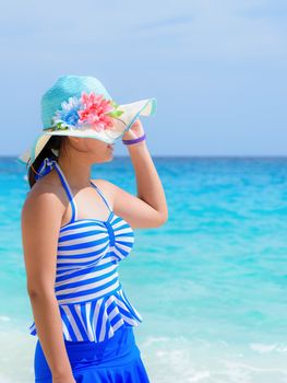 Tourist girl in a blue white striped swimsuit standing look at sea with happiness on the beautiful beach during summer at Koh Miang Island, Mu Ko Similan National Park, Phang Nga province, Thailand