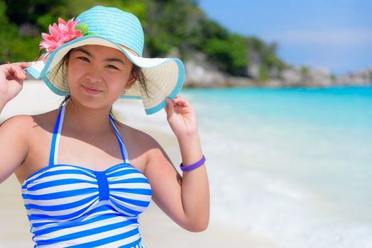 Tourist girl in blue white striped swimsuit standing pose with happy on the beautiful beach and sea during summer at Koh Miang Island, Mu Ko Similan National Park, Phang Nga Province, Thailand