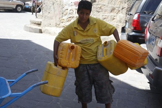 YEMEN, Taiz: A Yemeni boy carries jerrycans to fill them with water during a distribution of food and clean water in the Nasser school, outside Taiz (Ta'izz), western Yemen, on October 23, 2015. Many Yemenis are suffering from lack of basic services and resources, in a humanitarian disaster dramatically worsened by a blockade imposed by the Saudi-led coalition.