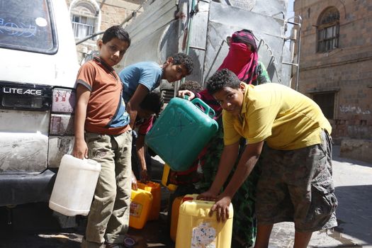 YEMEN, Taiz: Yemeni boys carry jerrycans to fill them with water during a distribution of food and clean water in the Nasser school, outside Taiz (Ta'izz), western Yemen, on October 23, 2015. Many Yemenis are suffering from lack of basic services and resources, in a humanitarian disaster dramatically worsened by a blockade imposed by the Saudi-led coalition.