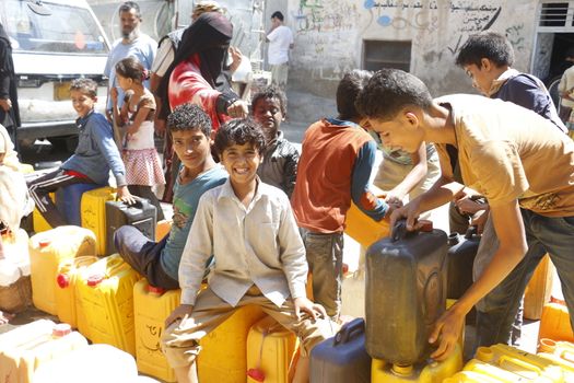 YEMEN, Taiz: Yemeni boys carry jerrycans to fill them with water during a distribution of food and clean water in the Nasser school, outside Taiz (Ta'izz), western Yemen, on October 23, 2015. Many Yemenis are suffering from lack of basic services and resources, in a humanitarian disaster dramatically worsened by a blockade imposed by the Saudi-led coalition.