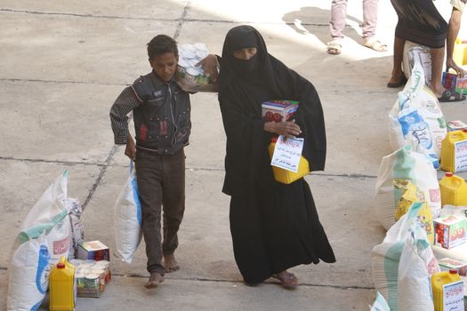 YEMEN, Taiz: A Yemeni woman and her son carry bags of supplies during a distribution of food and clean water in the Nasser school, outside Taiz (Ta'izz), western Yemen, on October 23, 2015. Many Yemenis are suffering from lack of basic services and resources, in a humanitarian disaster dramatically worsened by a blockade imposed by the Saudi-led coalition.