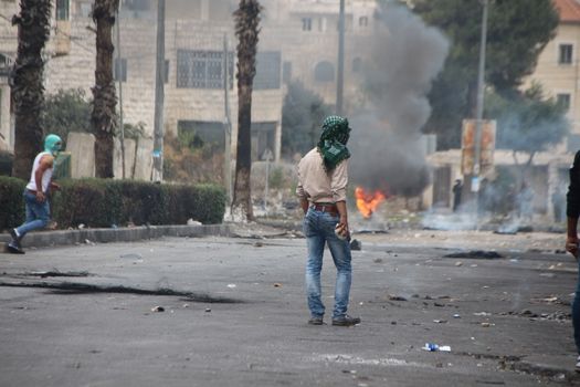 WEST BANK, Hebron: A Palestinian protester holds a stone to throw it at Israeli security forces during clashes on October 23, 2015, following Friday prayers in Ras e-Jura, in the northern entrance of Hebron, West Bank. Israel lifted age restrictions for the main weekly prayers at Jerusalem's flashpoint Al-Aqsa mosque compound, in an apparent bid to ease tensions over the site that sparked a surge in Israel-Palestinian violence. 