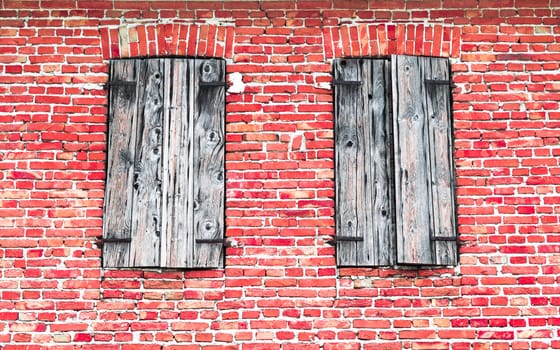Windows with wooden frames on red brick wall.