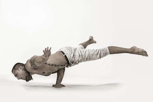 Muscular Shirtless Male Acrobatic Dancer Balancing on Arm and Hand in Studio Isolated on White Background