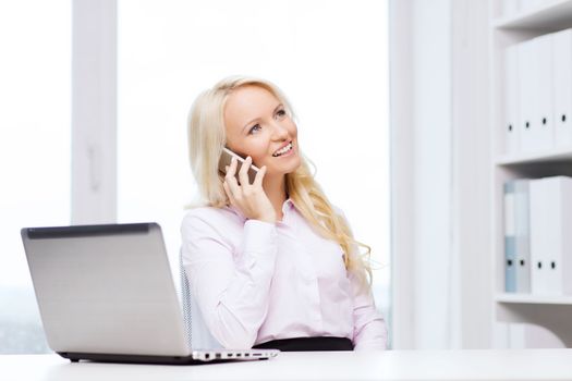 education, business, communication and technology concept - smiling businesswoman or student with laptop computer calling on smartphone in office