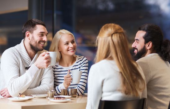 people, leisure, communication, eating and drinking concept - happy friends meeting and drinking tea or coffee at cafe