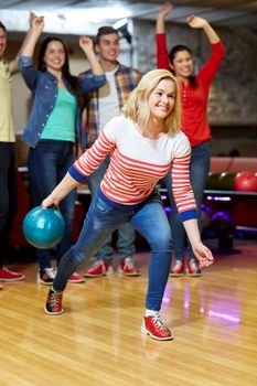 people, leisure, sport and entertainment concept - happy young woman throwing ball in bowling club