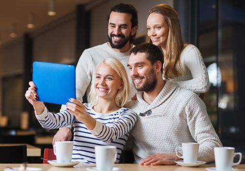 people, leisure, technology and friendship concept - happy friends with tablet pc computer taking selfie at cafe