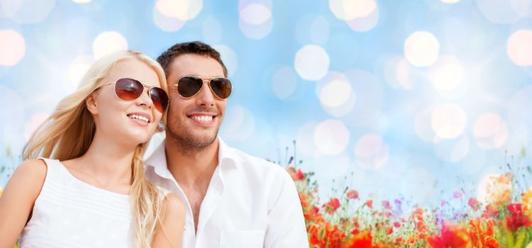 summer holidays, people and dating concept - happy couple in shades over blue lights and poppy field background