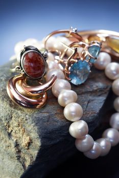 Set of various jewelry adornments on stone against dark background